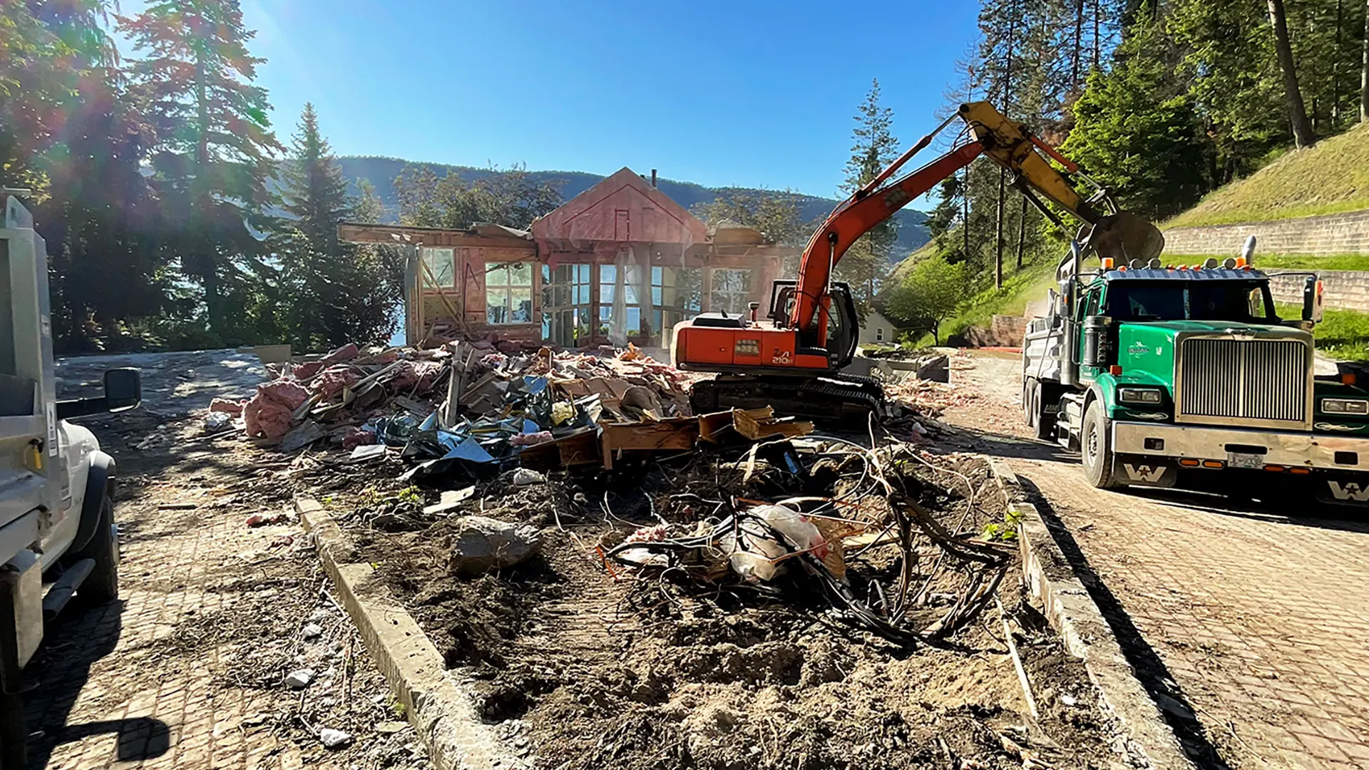 Excavator loading a dumptruck demolishing a house